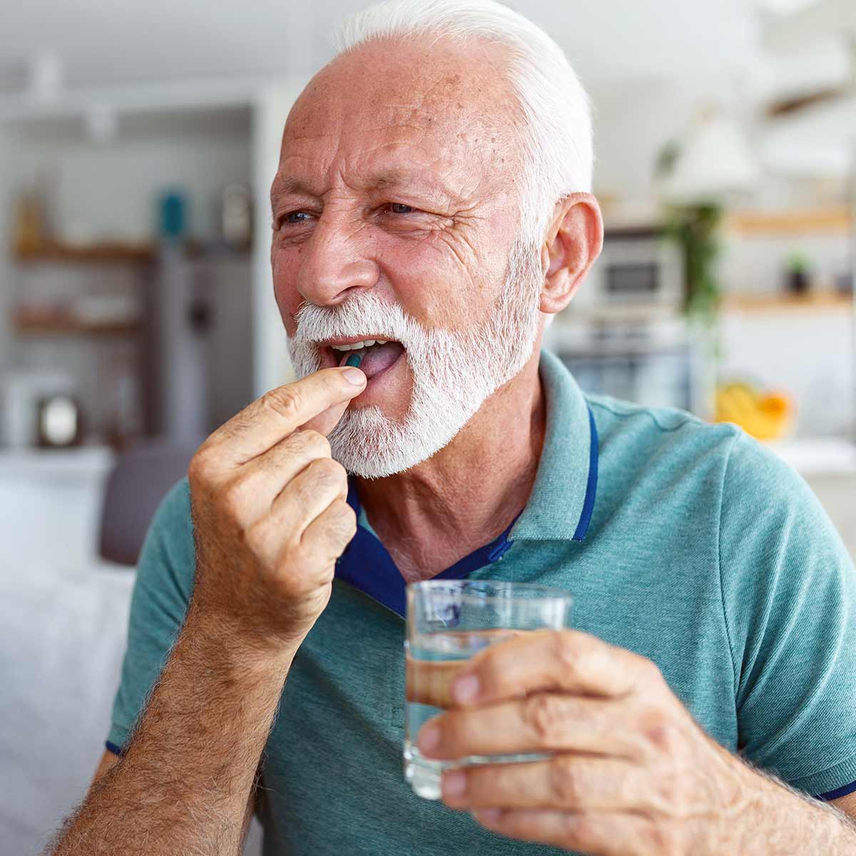 older man taking capsule supplement