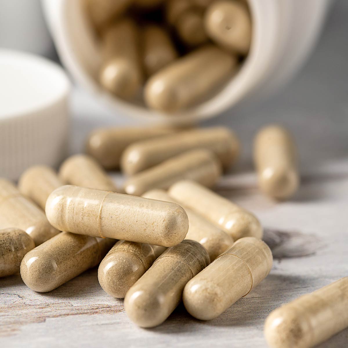 herbal supplement capsules pouring out of a supplement bottle onto a table