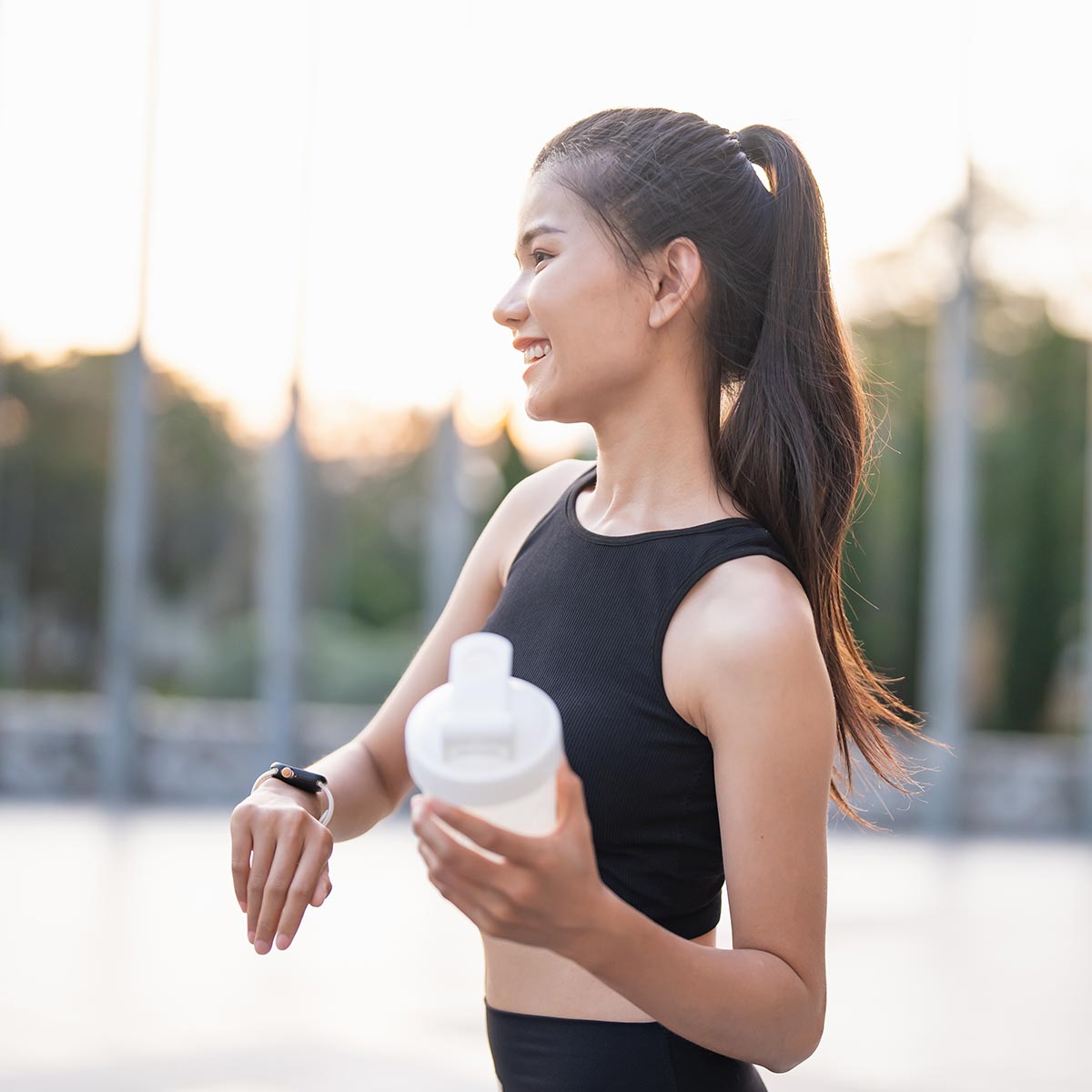 woman stopping in the middle of her job to check her vitals and drink a protein powder shake