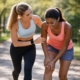 two women jogging and one of them experiencing muscle strain