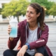a woman drinking an electrolyte beverage on a break from jogging