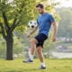 man concentrating on bouncing a soccer ball on his knee